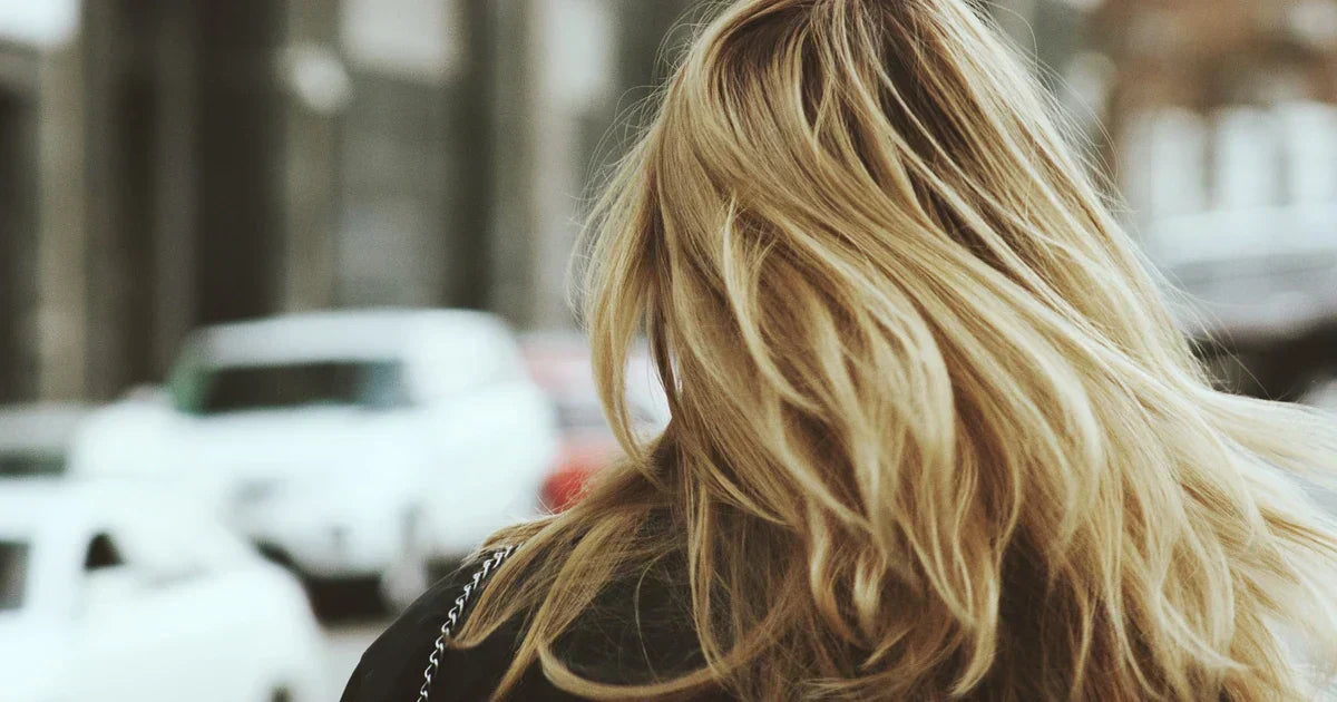 Mujer con cabello rubio en entorno urbano, cuidado de cuero cabelludo sensible