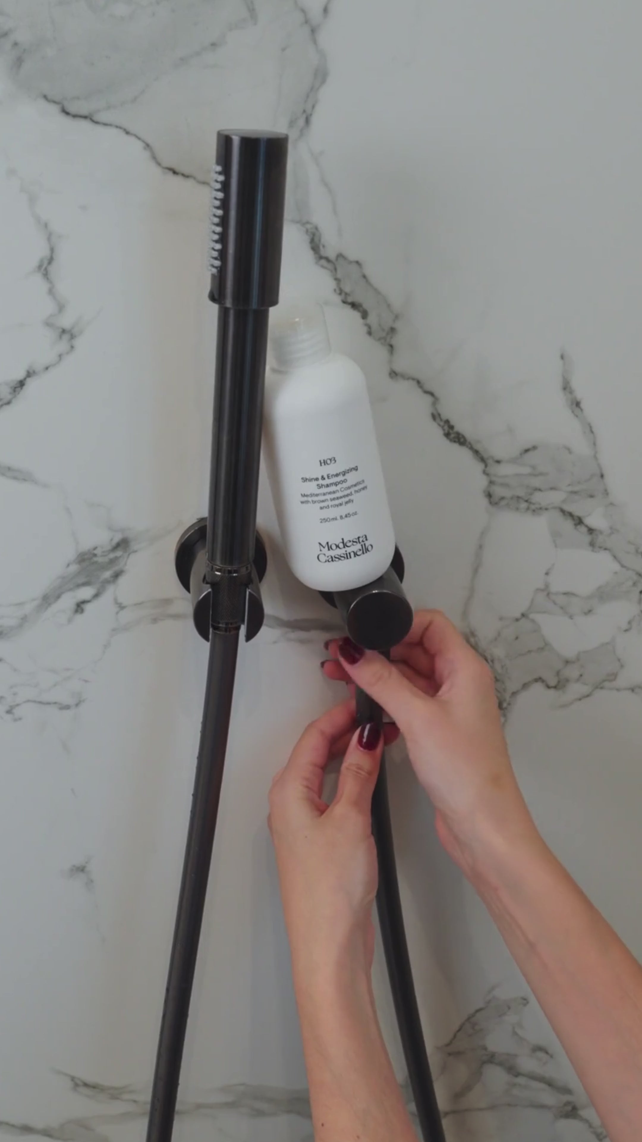 Envase de champú Modesta Cassinello montado en soporte de pared, siendo utilizado en la ducha.
