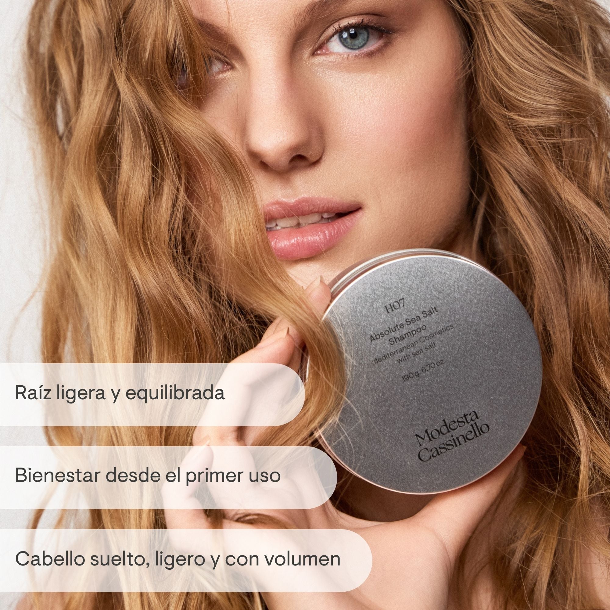 Mujer con cabello ondulado y ligero sosteniendo el champú con sal marina H07 de Modesta Cassinello, raíz ligera y equilibrada, cabello suelto y con volumen desde el primer uso